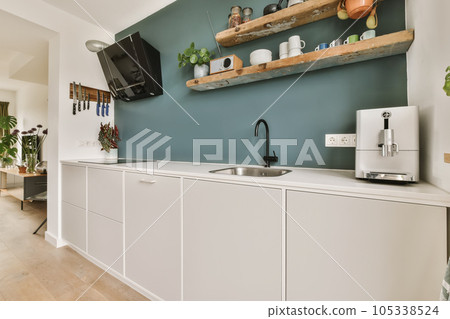 a kitchen with blue walls and white cupboards on the wall, there is a tv mounted above the sink a kitchen with blue walls and white cupboards on the wall, there is a tv mounted above the sink 105338524