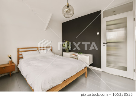a bedroom with a bed, nightstand and mirror in the corner area on the left hand side of the room a bedroom with a bed, nightstand and mirror in the corner area on the left hand side of the room 105338535