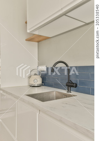 a kitchen with white cabinets and blue subway tiles on the wall behind it is a sink, fauced 105338540
