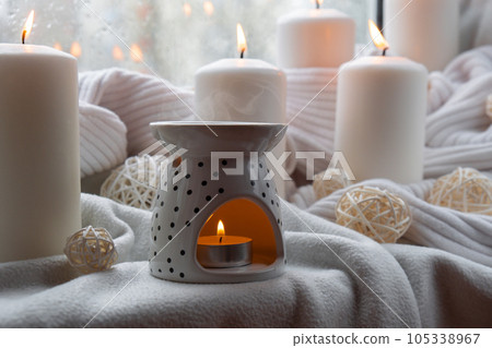 Aroma lamp with essential oil, aromatherapy at home, burning candle, dropping essential oil. Concept of home relaxation and anti stress. Natural Spa treatment Home fragnance at cozy home on the Aroma lamp with essential oil, aromatherapy at home, burning candle, dropping essential oil. Concept of home relaxation and anti stress. Natural Spa treatment Home fragnance at cozy home on the 105338967