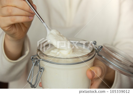 Unrecognizable woman eating from Glass jar natural organic homemade yogurt. Immunity-boosting ingredients. Concept of healthy eating breakfast of Greek yogurt 105339012