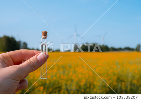 Hand holding test tube with liquid on background of canola flowers field blooming farm. Rapeseed oil over natural background. Farmer soil sample in tube chemical analysis ph test. Agrochemical Hand holding test tube with liquid on background of canola flowers field blooming farm. Rapeseed oil over natural background. Farmer soil sample in tube chemical analysis ph test. Agrochemical 105339207