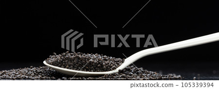 Black Sesame seeds flying explosion, black grain wave floating. Abstract cloud fly splash in air. Sesame seed is material food.  Black background Isolated selective focus blur 105339394