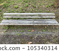 A decaying wooden bench and sunlight filtering through the trees in summer 105340314