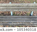 A decaying wooden bench and sunlight filtering through the trees in summer 105340318
