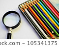 Colorful colored pencils and a magnifying glass on a white sheet of paper 105341375