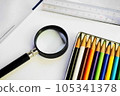 Colorful colored pencils, a magnifying glass and a ruler on a white sheet of paper 105341378