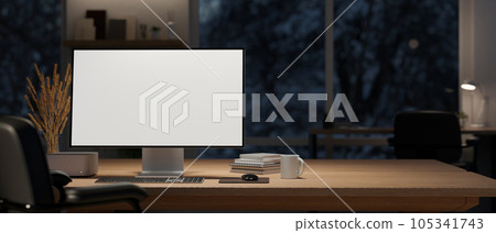 A computer mockup and decor on a wooden table in a modern dark office room at night. 105341743