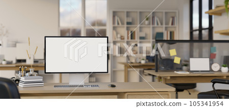 A computer mockup is on an office desk in a modern office co-working room. 105341954