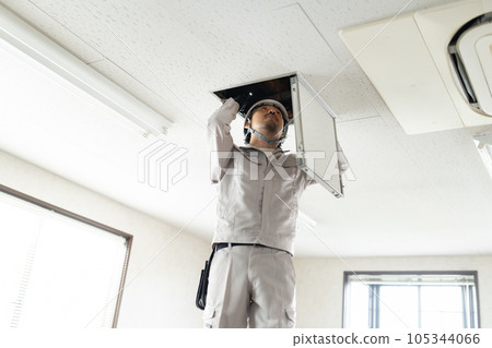 Male worker checking the ceiling inspection door Male worker checking the ceiling inspection door 105344066