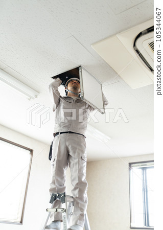 Male worker checking the ceiling inspection door 105344067