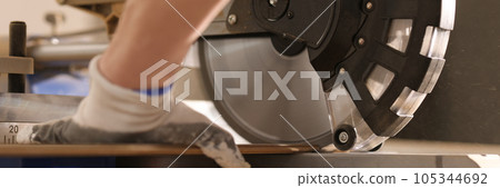 Construction worker sawing wooden board with power end saw closeup 105344692