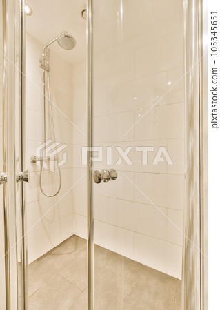 a shower room with white tile walls and flooring, it is very nice to see the light coming through the glass door 105345651