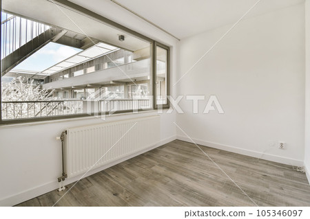 an empty room with wooden floors and white walls, there is a large window that looks out onto the street an empty room with wooden floors and white walls, there is a large window that looks out onto the street 105346097