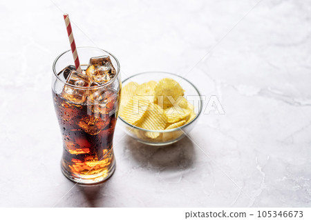 Refreshing glass of cola with ice, accompanied by a serving of crispy chips Refreshing glass of cola with ice, accompanied by a serving of crispy chips 105346673