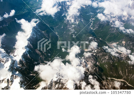Beautiful window view of fluffy clouds and Alps mountains from passenger seat on airplane. Travel and air transportation Beautiful window view of fluffy clouds and Alps mountains from passenger seat on airplane. Travel and air transportation 105347780