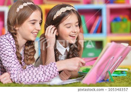 Two school age kids doing their homework on floor at home. Brother and sister siblings children drawing together, preparing for school lesson. Homeschool concept. Two school age kids doing their homework on floor at home. Brother and sister siblings children drawing together, preparing for school lesson. Homeschool concept. 105348357