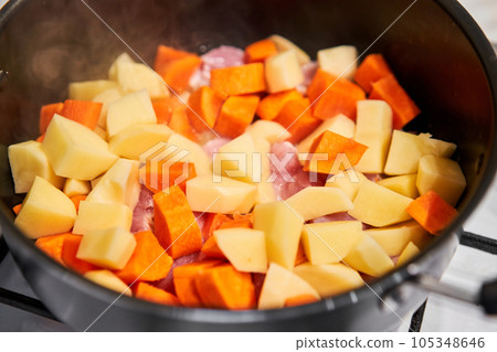 We prepare healthy food. Chicken breast in pieces with potatoes and carrot in a saucepan simmer on low heat. Home cooking. Healthy food, cooked without oil and salt. 105348646