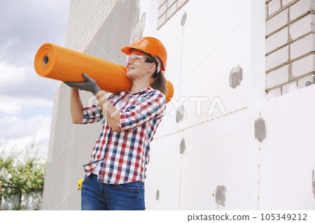 The woman with rolls of reinforcing fiberglass. Insulation of the house with polyfoam board on the facade The woman with rolls of reinforcing fiberglass. Insulation of the house with polyfoam board on the facade 105349212