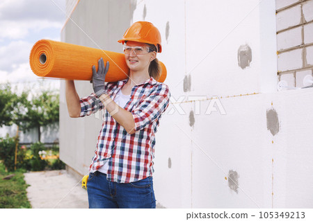 The woman with rolls of reinforcing fiberglass. Insulation of the house with polyfoam board on the facade The woman with rolls of reinforcing fiberglass. Insulation of the house with polyfoam board on the facade 105349213