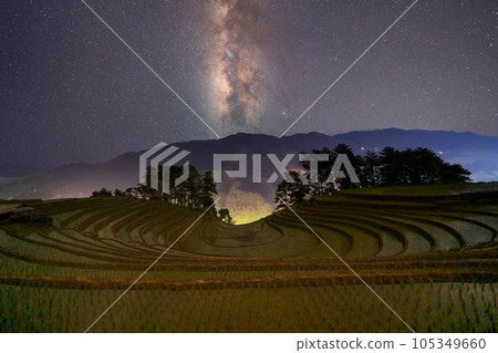 Fresh paddy rice terraces and milky way and stars on space, green agricultural fields in countryside or rural area of Mu Cang Chai, mountain hills valley in Asia, Vietnam. Nature landscape at night. Fresh paddy rice terraces and milky way and stars on space, green agricultural fields in countryside or rural area of Mu Cang Chai, mountain hills valley in Asia, Vietnam. Nature landscape at night. 105349660