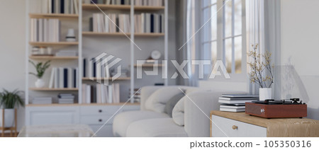 A vintage record player on a drawer by a cozy couch in a modern and cozy white living room. 105350316