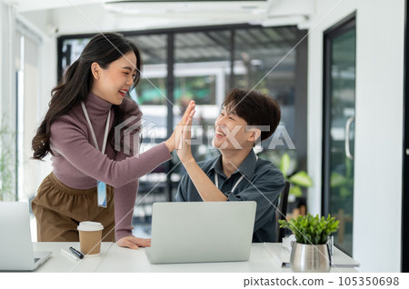 Two cheerful business people give high fives to each other to celebrate their successful project Two cheerful business people give high fives to each other to celebrate their successful project 105350698