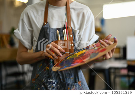 Artist holding palette and brush standing in bright studio. Art, education, creativity and people concept Artist holding palette and brush standing in bright studio. Art, education, creativity and people concept 105351559