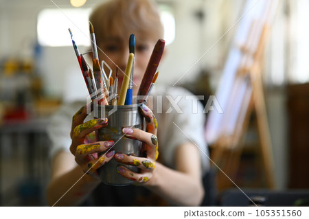 Image of male artist in apron holding metal bucket with different brushes of the artist. Art, education, creativity and people Image of male artist in apron holding metal bucket with different brushes of the artist. Art, education, creativity and people 105351560