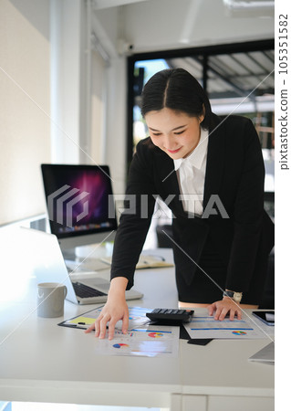 Professional businesswoman analyzing sales statistics document at office desk Professional businesswoman analyzing sales statistics document at office desk 105351582