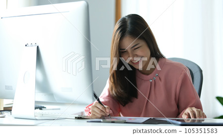 Cheerful Asian woman entrepreneur watching online webinar on computer screen and making importance notes Cheerful Asian woman entrepreneur watching online webinar on computer screen and making importance notes 105351583