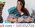 The cat lies on the lap of a young woman sitting in the garden at home. love between pet and people. 105352728