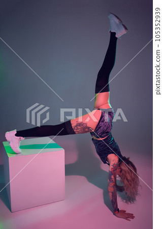 young beautiful blonde gymnast girl in velour blue booty shorts and black stockings standing upside down on pink background young beautiful blonde gymnast girl in velour blue booty shorts and black stockings standing upside down on pink background 105352939