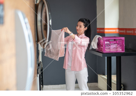 Young woman unloading washing machine in public laundry. Young woman unloading washing machine in public laundry. 105352962