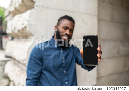 Bearded young dark-skinned man with a phone Bearded young dark-skinned man with a phone 105353027