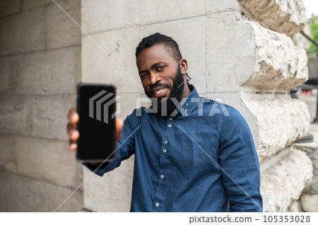 Bearded young dark-skinned man with a phone Bearded young dark-skinned man with a phone 105353028
