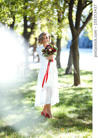 Beautiful bride with wedding bouquet in park. Elegant woman with professional make up and hair style 105353437