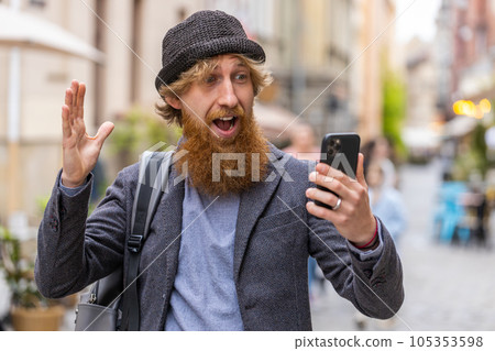 Excited happy winner young man use smartphone celebrating win good message news in city street Excited happy winner young man use smartphone celebrating win good message news in city street 105353598