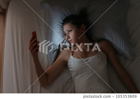 Girl can't sleep and checking her mobile phone in bed at night. Girl can't sleep and checking her mobile phone in bed at night. 105353609