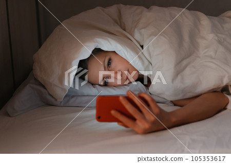 Young woman can't sleep and using her smartphone in beg at night. Young woman can't sleep and using her smartphone in beg at night. 105353617