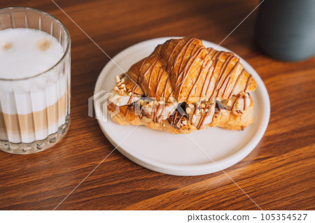Croissant with chocolate and banana inside on a white plate with a cup of coffee 105354527