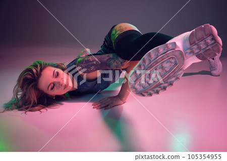 beautiful caucasian blonde girl in velour blue booty shorts and black stockings dancing twerk lying down on pink background 105354955