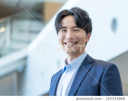 Portrait of a young smiling man standing in the lobby of an office building 105354968