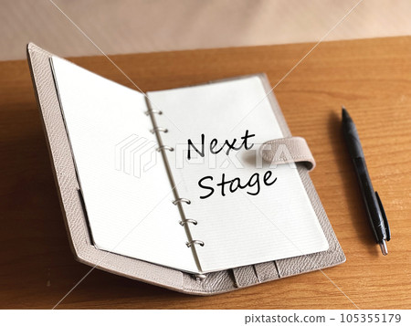 Open notebook and ballpoint pen _NextStage with letters 105355179