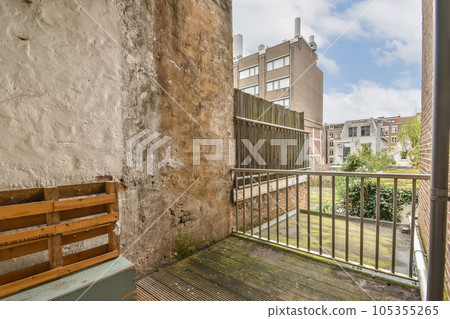 an empty balcony with a bench in the middle part of the room, looking out to the street and buildings 105355265