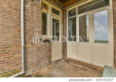 a brick house with two doors and an open window on the front door there is a blue sky in the background 105355267