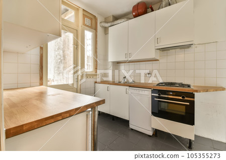 a kitchen with white cupboards and wood counter tops on the island in front of the sink is an oven a kitchen with white cupboards and wood counter tops on the island in front of the sink is an oven 105355273