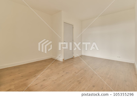 an empty room with wood floors and white walls, there is a door leading to the left side of the room an empty room with wood floors and white walls, there is a door leading to the left side of the room 105355296