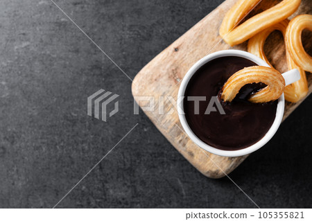 Traditional Spanish churros with hot chocolate on black slate background 105355821