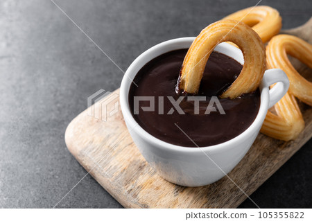 Traditional Spanish churros with hot chocolate on black slate background Traditional Spanish churros with hot chocolate on black slate background 105355822